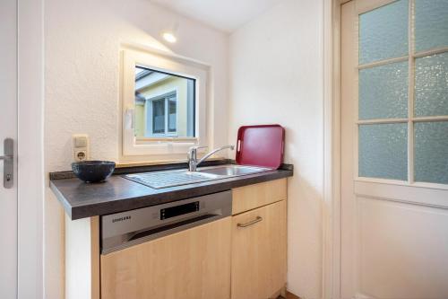 Una pequeña cocina con fregadero y espejo. en Prerow Am Deich - Ferienwohnung 4, en Prerow