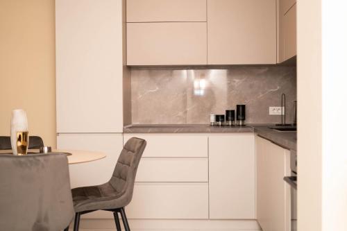 a kitchen with white cabinets and a table and a chair at Urban Living in Gevgelija