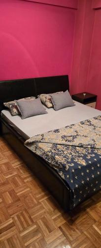 a bed in a room with a pink wall at Apartman Aylin 2 in Tuzla