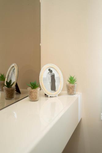 a white counter with two potted plants and a mirror at Urban Living in Gevgelija