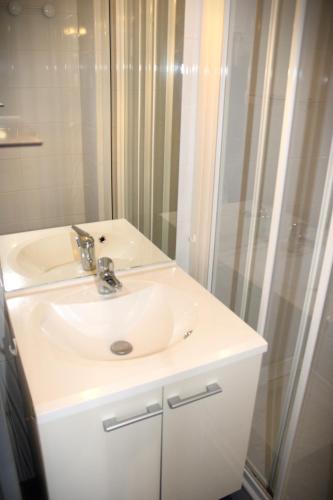 une salle de bain avec un lavabo blanc et une douche dans l'établissement Capipa, au Cap d'Agde