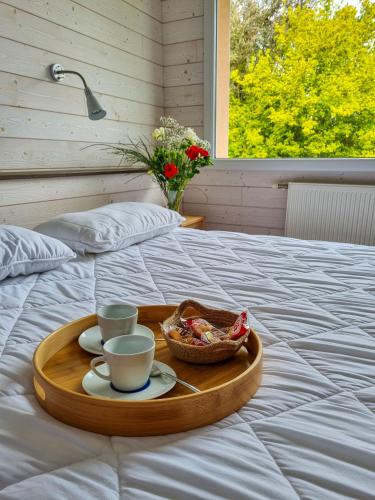 a tray with cups and a basket of food on a bed at Résidence de Nodeven in Guissény