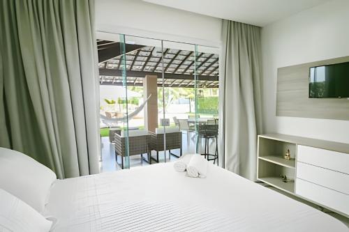 una camera da letto con un letto e un balcone con un tavolo di Casa Malu 5 Suítes 50 Metros do MAR Guarajuba-BA a Monte Gordo