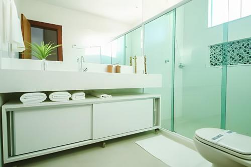 un bagno bianco con lavandino e WC di Casa Malu 5 Suítes 50 Metros do MAR Guarajuba-BA a Monte Gordo