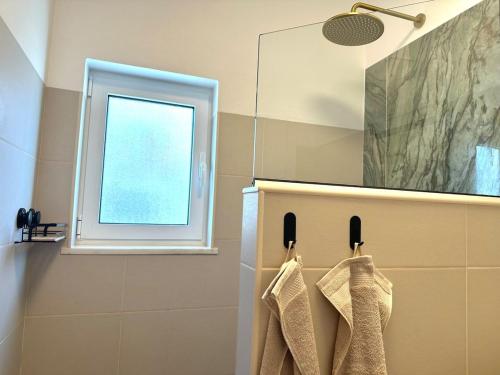 ein Bad mit einem Fenster und Handtüchern auf einem Kleiderständer in der Unterkunft Onda House Cozy Surf House in Odeceixe