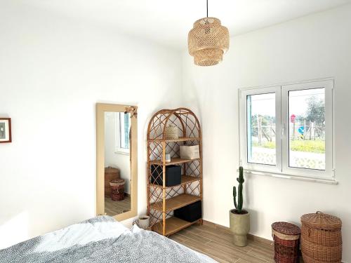 ein Schlafzimmer mit einem Bett, einem Spiegel und einem Regal in der Unterkunft Onda House Cozy Surf House in Odeceixe