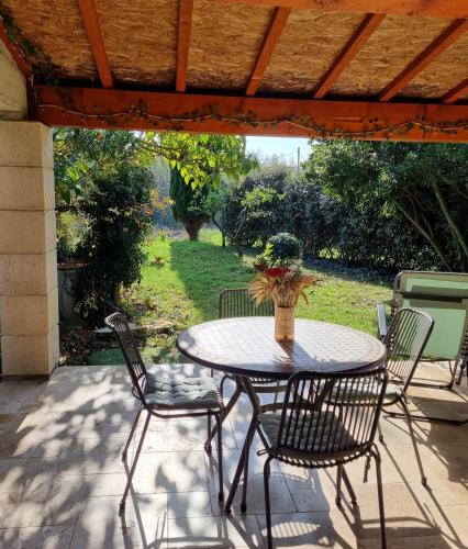 - une table avec des chaises et un vase de fleurs sur la terrasse dans l'établissement Maison en pleine nature, à Saint-Christol-de-Rodières