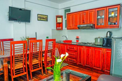 cocina con armarios rojos, mesa y sillas en Mountain Breeze Apartment, en Nuwara Eliya