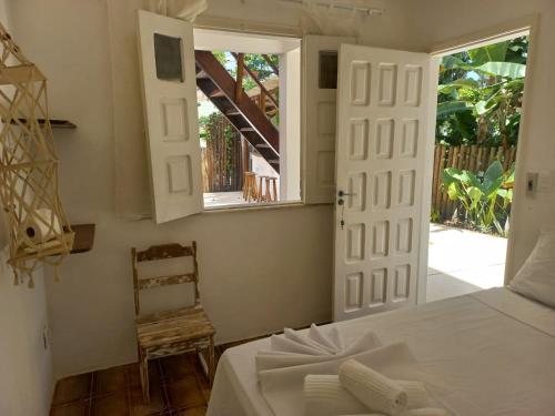 a bedroom with a bed and a window and a chair at Vilare Pousada in Morro de São Paulo