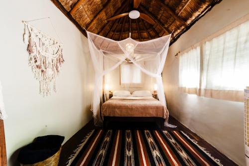 a bedroom with a bed with a mosquito net at Eco Bañitas Tulum in Tulum