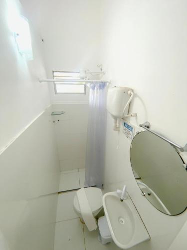 a white bathroom with a toilet and a mirror at Vilare Pousada in Morro de São Paulo