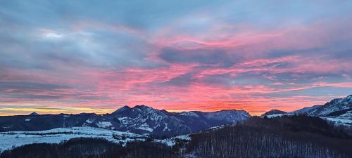 a sunset over a snow covered mountain range at Dream view of Apuseni in Rîmeţi