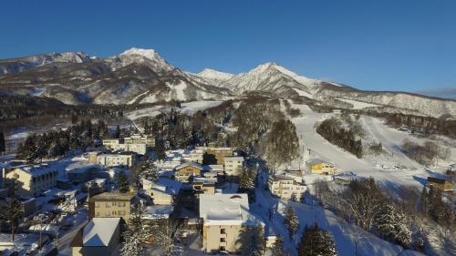 a town in the snow with mountains in the background at Kogakuro in Myoko