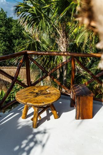 a wooden bench and stool next to a fence at Eco Bañitas Tulum in Tulum