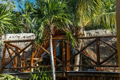 a wooden fence with palm trees behind it at Eco Bañitas Tulum in Tulum