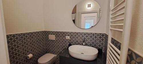 a bathroom with a sink and a toilet and a mirror at Urban Charme Palau in Palau