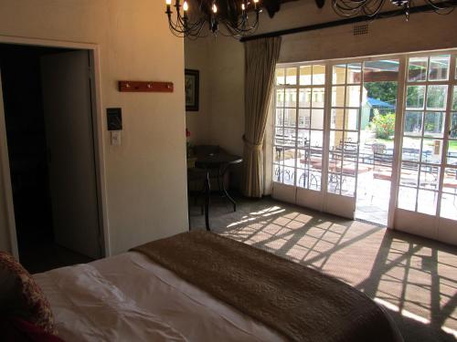 a bedroom with a bed and a door to a patio at Thatchfoord Lodge in Johannesburg