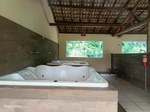 a large white tub in a room with two windows at Aldeia das águas Park Resort - Flat D308 Village das Águas in Barra do Piraí