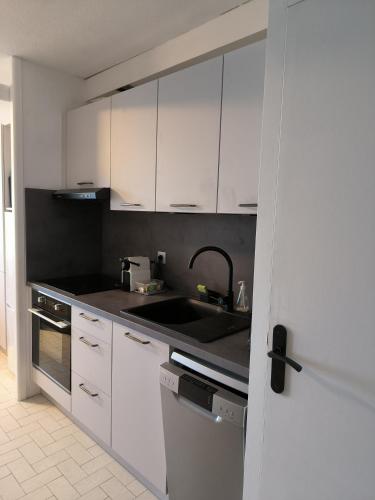 une cuisine avec des armoires blanches et un évier dans l'établissement Appartement Front de mer CIMER, à Canet