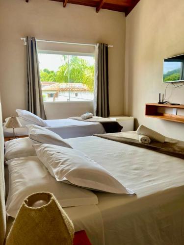 two beds in a room with a window at Pousada Maré Mansa in Paraty