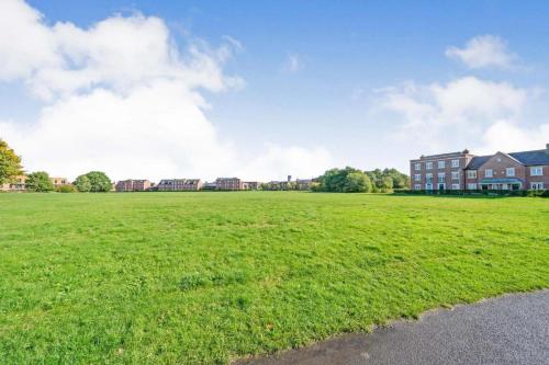 a large field of green grass with houses in the background at Executive, 3-storey town house in Runcorn