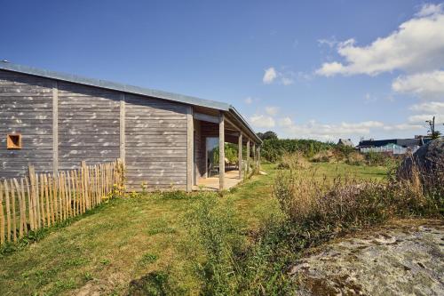 a building with a fence next to a field at Maison moderne, ambiance californienne, proche mer in Plouescat