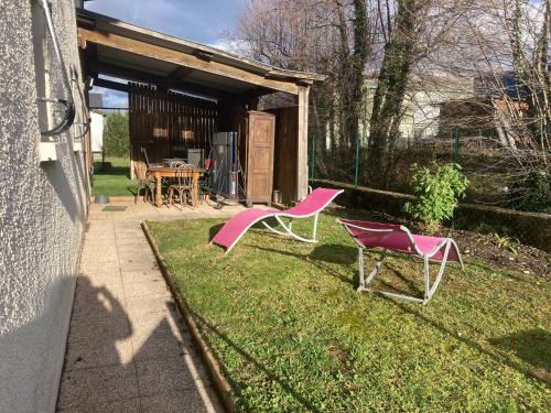 two pink chairs in the yard of a house at Entre lac et montagne in Le Bourget-du-Lac