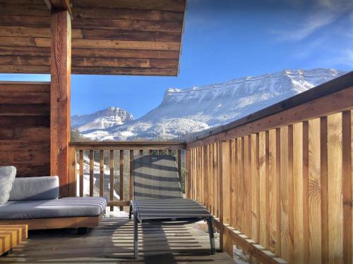 une chaise et un canapé sur une terrasse avec une montagne enneigée dans l'établissement Chalet Emeraude des Alpes - OVO Network, à Saint-Pierre-dʼEntremont