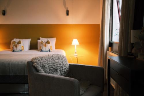 a bedroom with a bed and a chair and a lamp at Guesthouse De Wissen in Dilsen-Stokkem