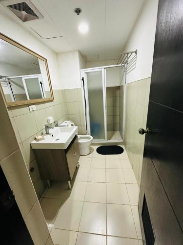 a bathroom with a sink and a toilet and a shower at Cozy Mines View Apartment in Baguio