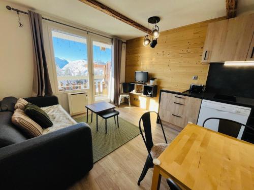 un salon avec un canapé et une cuisine dans l'établissement T2 4 personnes - Proche pistes, à Huez
