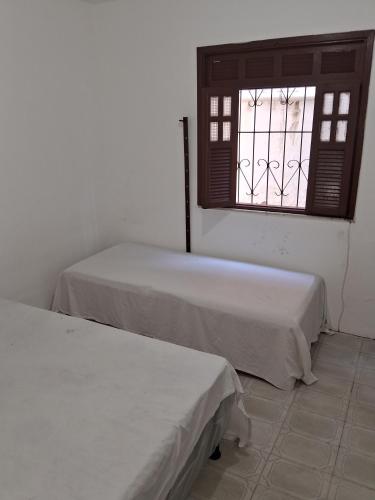 two beds in a room with a window at Lauro de Freitas quartos para temporada do Carnaval in Lauro de Freitas