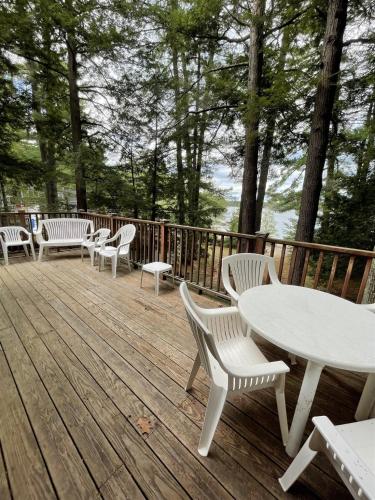 a deck with white tables and chairs and trees at SUNSET HAVEN LIMIT 8 cottage in Gray