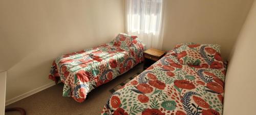 two beds and a chair in a room at Casa Fundadores in Puerto Montt
