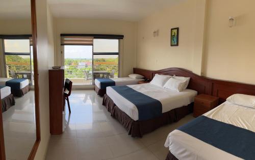 a hotel room with two beds and a balcony at Hotel Los Puentes Comfacundi in Girardot