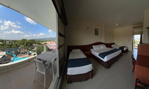 a hotel room with two beds and a balcony at Hotel Los Puentes Comfacundi in Girardot
