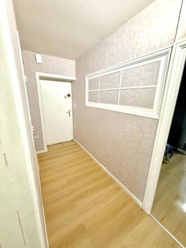 an empty room with a window and a wooden floor at Le Rétro - Appartement 2 chambres confortable et calme - Proche de toutes commodité - Stationnement facile à proximité in Saint-Laurent-sur-Saône