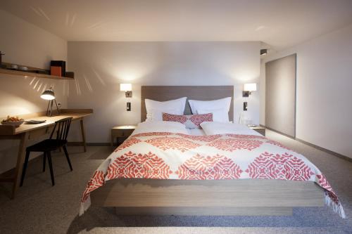 a bedroom with a large bed with a desk and a desk at Hotel Berghof in Lech am Arlberg