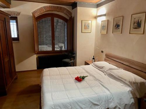 a bedroom with a white bed with a rose on it at Osteria Del Borgo B&B in Montepulciano
