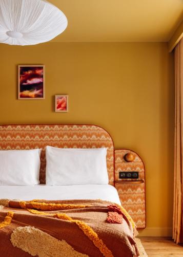 a bedroom with a bed with yellow walls at Le Jardin de Verre by Locke in Paris