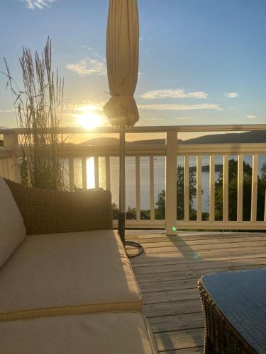 a balcony with a couch and the sunset on the ocean at Fräknero in Ljungskile