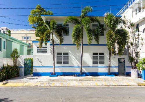 una casa bianca e blu con palme di fronte di 8 Atlantic Place by Stay with Bear a San Juan