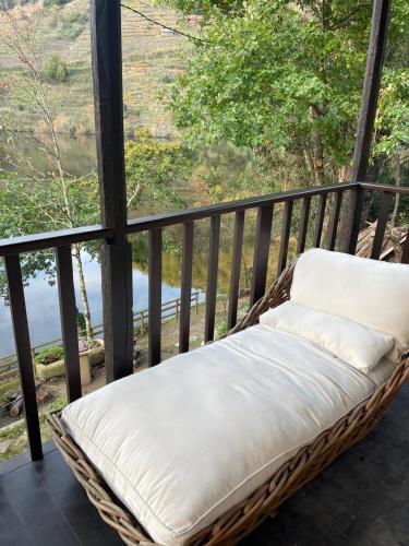 a wicker bench sitting on a balcony with a view at Casa Escondida Aveiga in Chantada