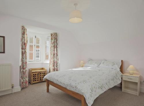 a white bedroom with a bed and a window at 1a Park Lane in Southwold