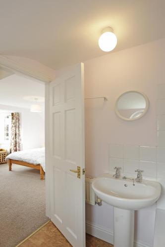 a white bathroom with a sink and a mirror at 1a Park Lane in Southwold