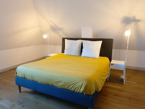 Cette chambre comprend un lit avec des draps jaunes et des oreillers blancs. dans l'établissement Villa La Maringotte, à Honfleur