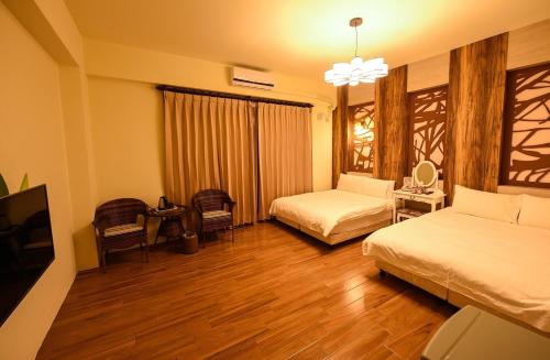 ein Hotelzimmer mit zwei Betten und einem Fernseher in der Unterkunft Summer Travel B&B in Taitung