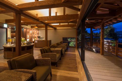 a restaurant with a bar with chairs and tables at Biwako Ryokusuitei in Otsu