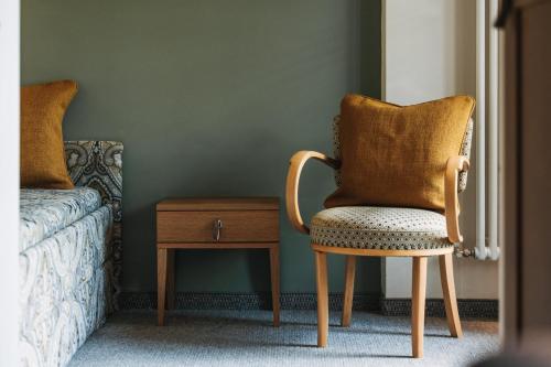 a bedroom with a chair next to a bed and a nightstand at Hotel Berghof in Lech am Arlberg