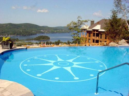 a large blue swimming pool with a view of a lake at Luxury Meets Adventure - Equinoxe 170-8 in Mont-Tremblant